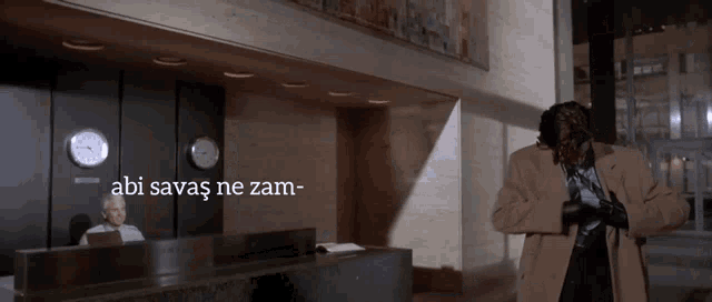 a man standing in front of a clock that says ' abi savaş ne zam ' on it