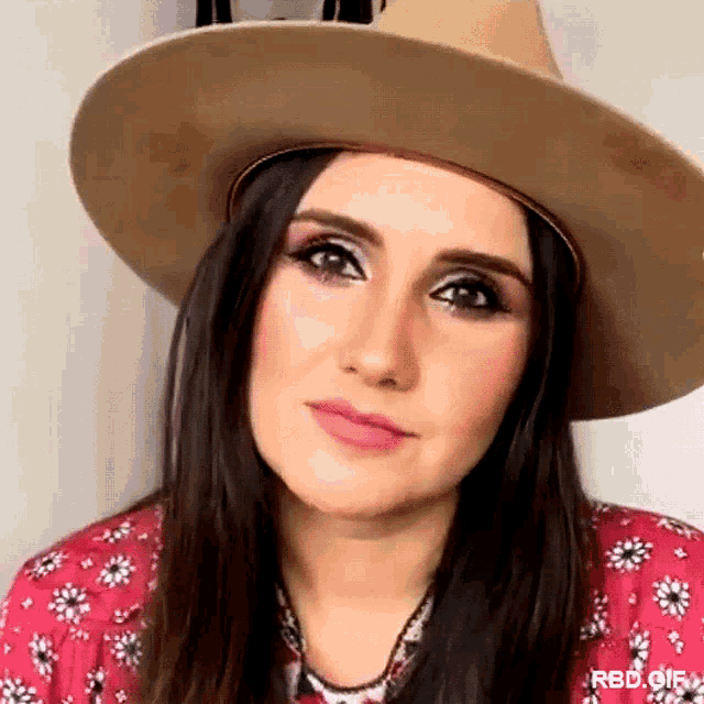 a close up of a woman wearing a hat and a red shirt