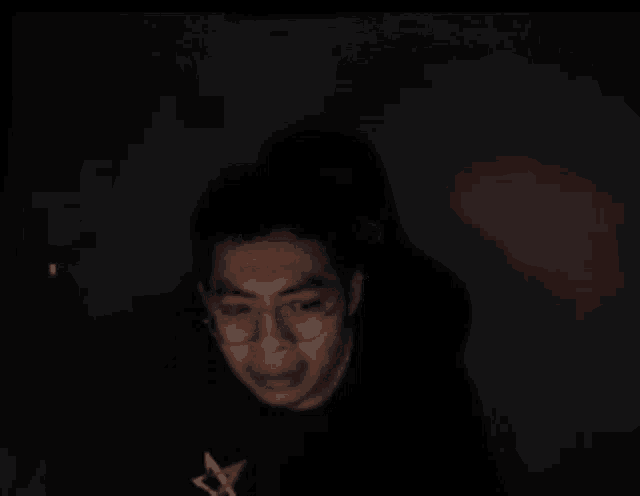 a man with glasses and a star on his shirt looks at the camera
