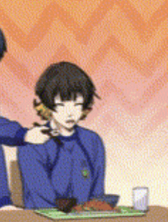 a man is putting a spoon in a woman 's mouth while sitting at a table .