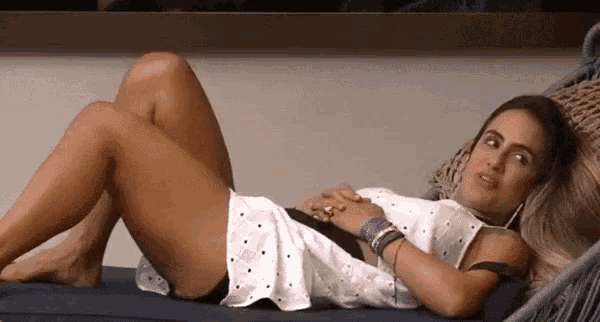 a woman in a white dress is laying on a couch with her legs crossed