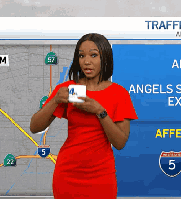a woman in a red dress is holding a cup of coffee in front of a map that says traffic