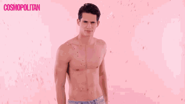 a shirtless man is standing in front of a pink background with cosmopolitan written on it