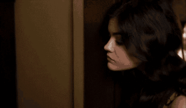 a woman with long black hair is standing in a doorway looking at the camera .