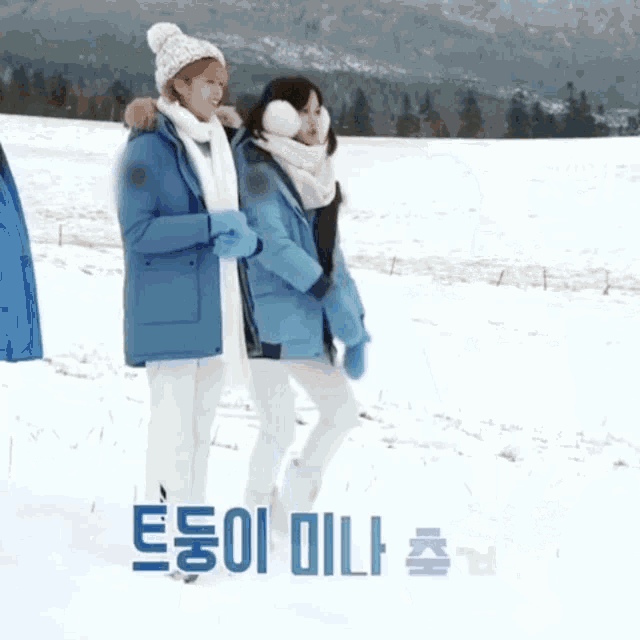 two women walking in the snow with korean writing on the bottom right