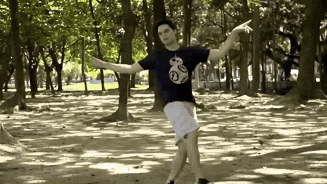 a man is dancing in a park wearing a star wars shirt .