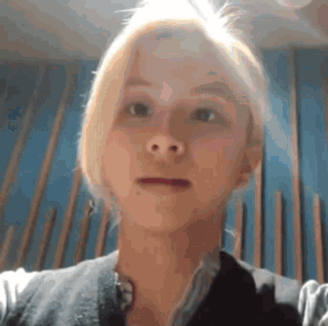 a woman with blonde hair is taking a selfie in a room with a blue wall .