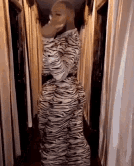 a woman in a zebra print dress is standing in a hallway with curtains .