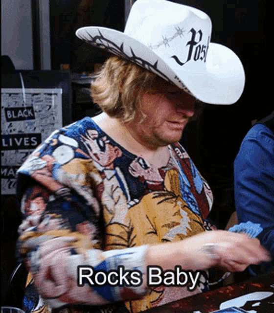 a man wearing a cowboy hat has rocks baby written on his shirt