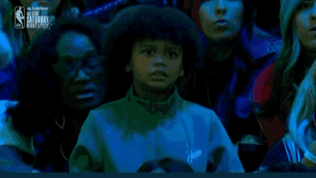 a young boy is crying in a crowd of people watching a basketball game sponsored by the nba