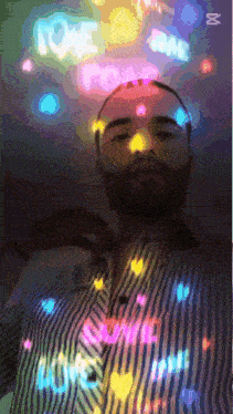 a man in a striped shirt is surrounded by colorful lights that say love