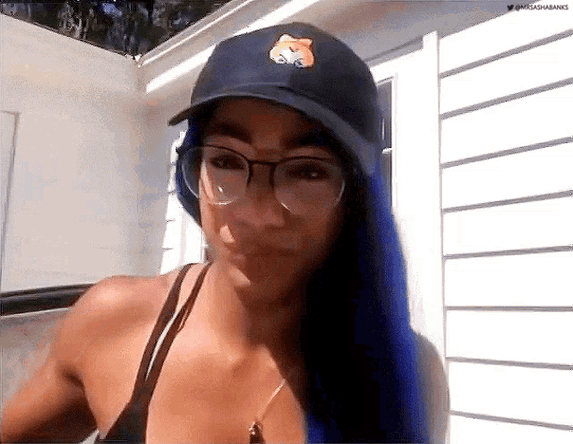 a woman wearing a hat and glasses is standing in front of a house .