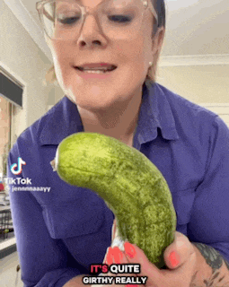 a woman wearing glasses is holding a cucumber and says it 's quite girthy really on the bottom