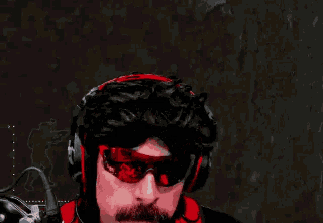 a man wearing headphones and sunglasses is waving