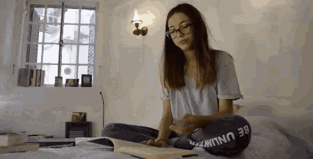 a girl is sitting on a bed reading a book