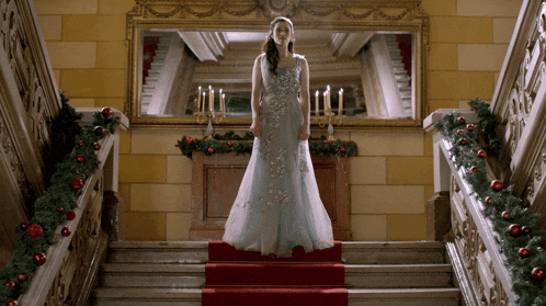 a woman in a blue dress is standing on a red carpet