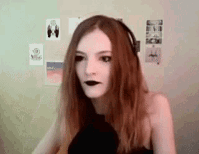 a woman wearing headphones and black lipstick is looking at the camera