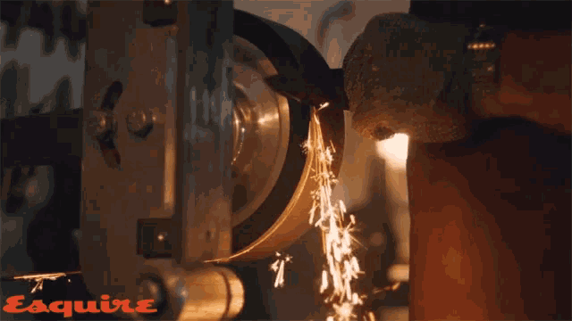 a person is sharpening a knife on a machine that says esquire on the bottom right