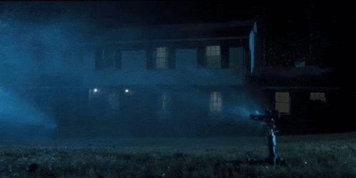 a house is lit up at night with a cross in the foreground