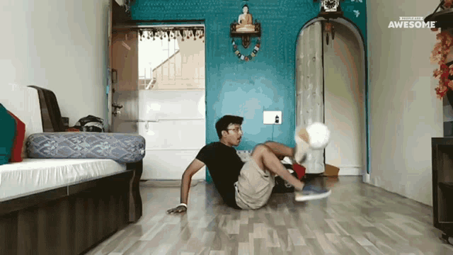 a man is kicking a soccer ball in a living room with awesome written on the corner