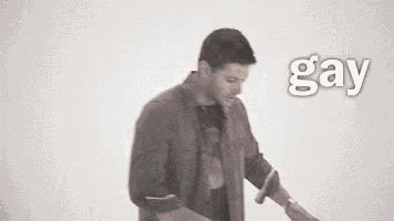 a man is dancing in front of a white wall with the word gay written on the bottom .