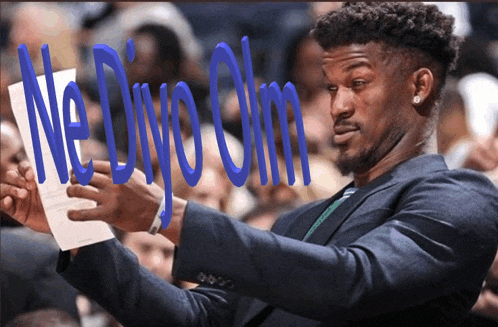 a man in a suit is holding a piece of paper with the words ne divo olm written on it