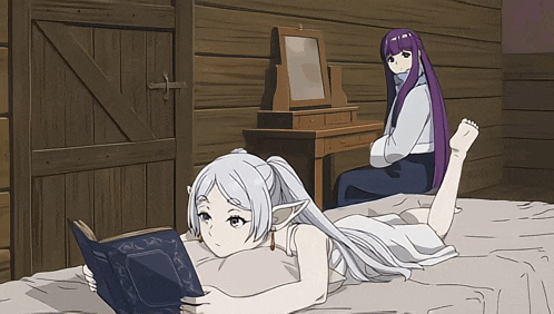 a girl laying on a bed reading a book while another girl sits at a desk