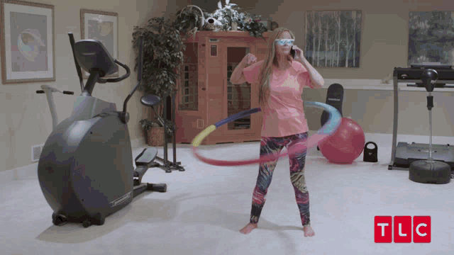 a woman hula hooping in a gym with tlc written in red