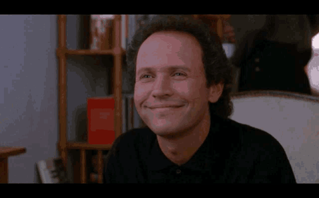 a man in a black shirt is smiling in a room