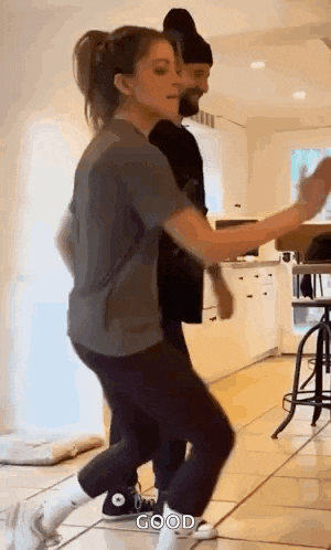 a woman is dancing in a kitchen with a man .