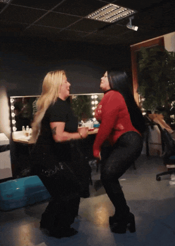 two women are dancing in a room and one is wearing a red sweater