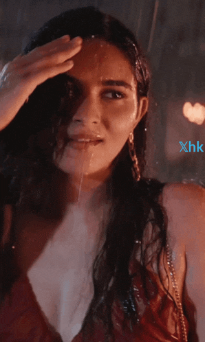 a woman in a red dress is standing in the rain with xhk written on the bottom right