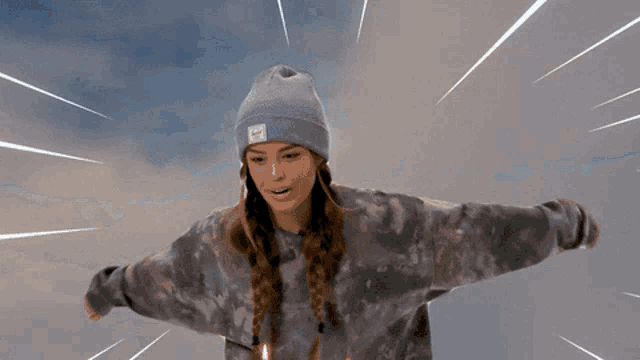 a girl wearing a purple beanie and a tie dye shirt is flying through the air
