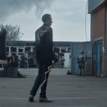 a man in a suit is holding a snake in front of a brick building