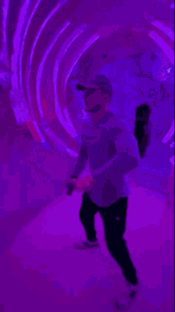 a man is dancing in a dark room with purple lights behind him .