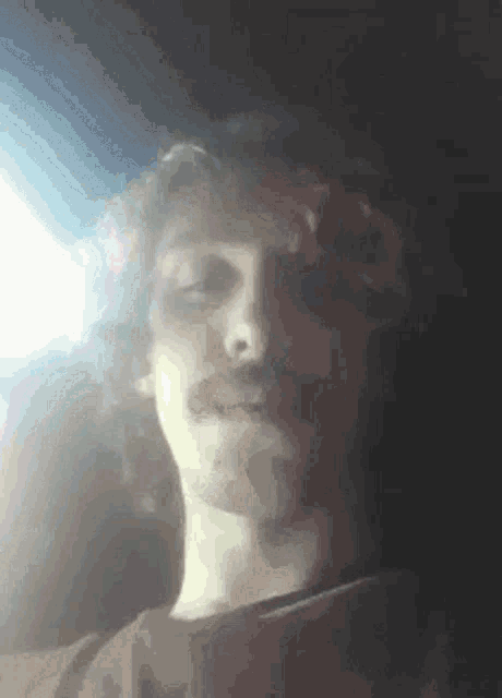 a man with a mustache is smoking a cigarette in a car