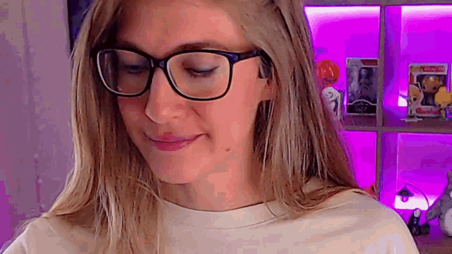 a woman wearing glasses is making a funny face in front of a purple wall .