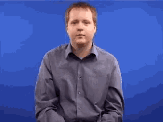 a man in a blue shirt is making a hand gesture