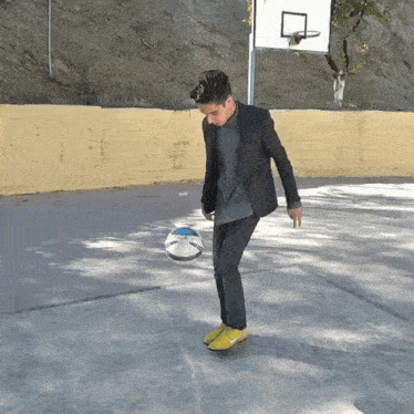 a man in a suit kicking a soccer ball on a court