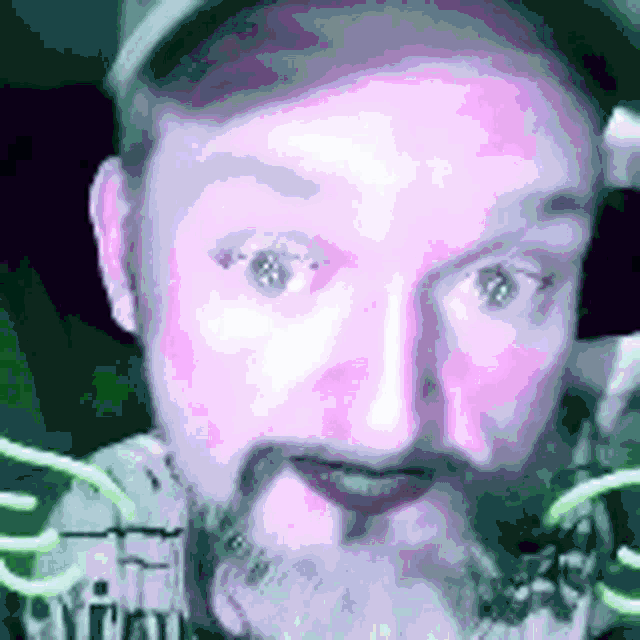 a man with a beard is wearing a hat and looking at the camera in a blurry photo .
