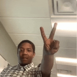 a man wearing a plaid shirt is giving a peace sign