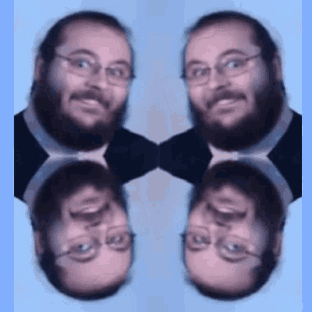 a man with glasses and a beard looks at his reflection in a mirror