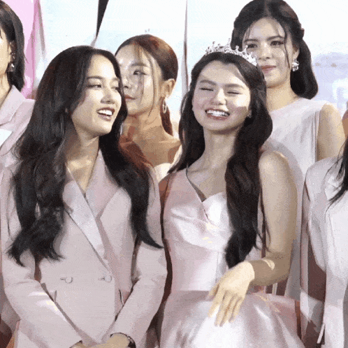 a group of women are posing for a picture and one of them is wearing a crown