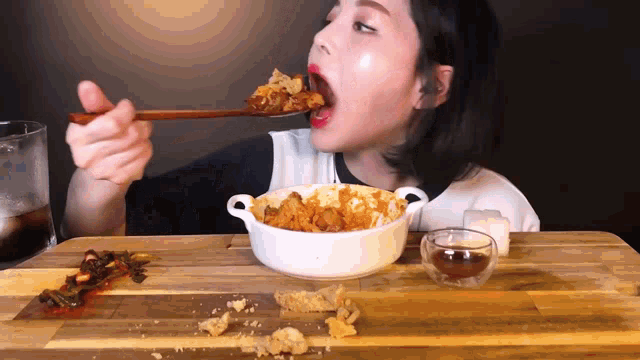 a woman is eating a bowl of food with a spoon in her mouth