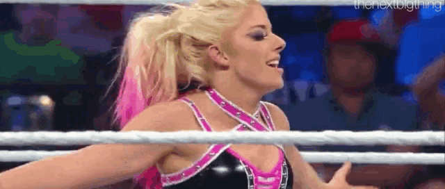 a female wrestler is standing in a wrestling ring .