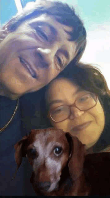 a man and a woman are posing with a dog