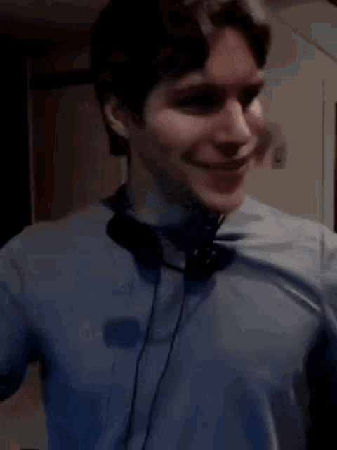 a man wearing headphones and a blue shirt is smiling and looking at the camera .