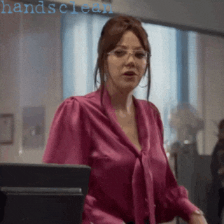 a woman wearing glasses and a pink blouse is standing in front of a computer screen with the words handsclean below her