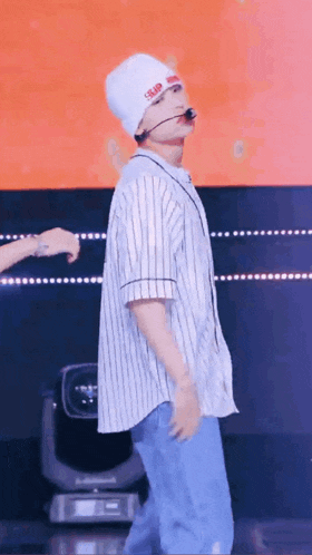 a man wearing a beanie and a striped shirt is dancing on a stage