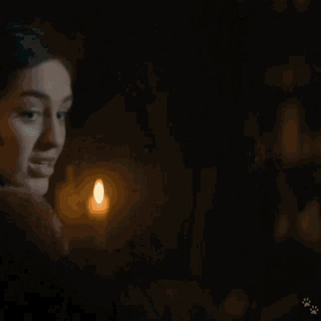 a woman in a blue dress stands in front of a candle